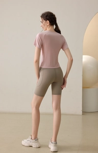 Side view of pink slim fit yoga t-shirt with drawstring and brown athletic biker shorts