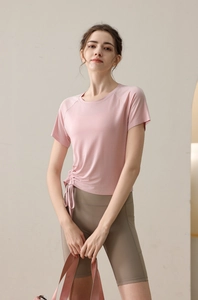 Detail of light pink yoga top with side drawstring cinch and high waist brown shorts