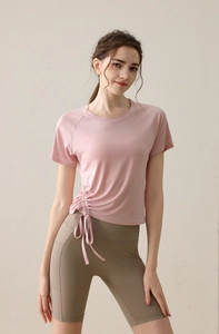 Detail of pink yoga top with drawstring side and high-waisted brown biker shorts