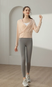 Détail d'un haut de yoga beige à capuche avec bandeau blanc et legging gris à taille haute