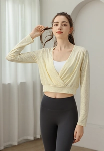 Detail of a pastel yellow lace wrap top for yoga with cross V-neck and mesh texture