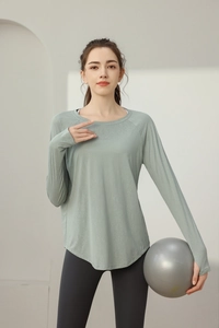 Λεπτομέρεια πράσινου yoga top με ζακάρ ύφασμα που αναπνέει και τρύπες για τους αντίχειρες