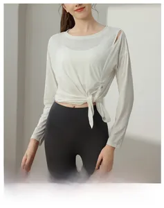 Detail of white long-sleeve yoga top with shoulder cutout and decorative waist tie knot