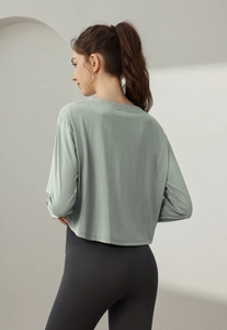 Détail d'un pull de yoga vert clair ample et d'un legging gris à taille haute pour femme