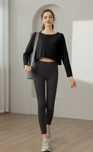 Haut de yoga noir ample et legging taille haute porté avec un tapis de yoga
