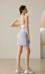 Side view of woman in light purple nylon sports shorts and white yoga bra for fitness