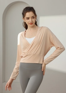 Détail d'un haut de yoga croisé pêche sur une brassière de sport blanche en intérieur