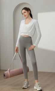 Close-up of a white V-neck yoga top and high-waisted grey leggings in a modern studio