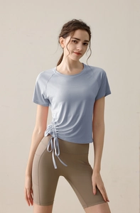 Detail of light blue yoga t-shirt with adjustable drawstring side and high waist brown leggings