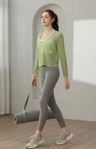 Gros plan sur le cache-cœur de yoga vert léger avec legging gris et tapis de yoga