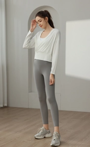 Haut de yoga blanc court pour femmes et legging gris dans un studio minimaliste