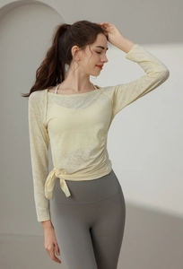 Detail of breathable yellow jacquard yoga top with drawstring hem and mesh texture
