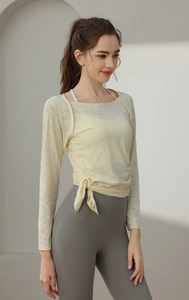 Detail of light yellow breathable jacquard yoga top with decorative waist tie and long sleeves