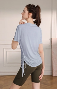 Detail of light blue yoga t-shirt with side drawstring and high-waist cycling shorts