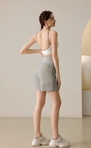 Slimming high-waisted gray yoga shorts and white sports bra on model, profile view