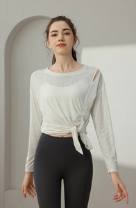 Close-up of white breathable yoga top with shoulder cutout and side waist tie detail