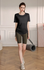 Detail of loose yoga top with side drawstrings and high waist green cycling shorts