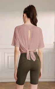 Detail of light pink yoga top with back oval cutout and knot design on mesh fabric