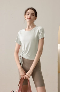 Detail of light green drawstring yoga top with side ruching and high waist brown shorts