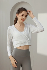 Close-up of white jacquard mesh yoga top with cross-waist design and breathable texture