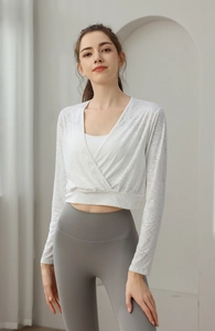 Detail of white nylon wrap yoga top with gray high-waisted leggings in minimalist interior