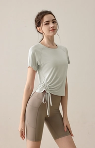 Detail of light green yoga top with side drawstring and high-waist brown cycling shorts