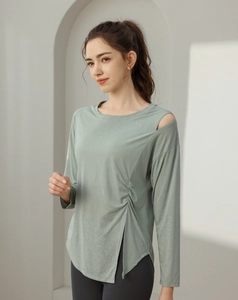 Detail of jade green yoga top with shoulder cutout, side ruching and split hem
