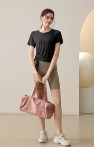 Detail of black sports T-shirt with side drawstrings and pink cylindrical gym bag