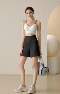 Full shot of women's nylon sports shorts with cream sports bra and fitness bag