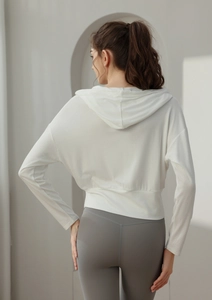 Détail d'un sweat à capuche court blanc et d'un legging gris montrant la silhouette de dos