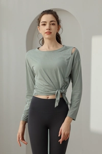 Detailed view of women's sage green yoga top featuring cold shoulder and side drawstring tie