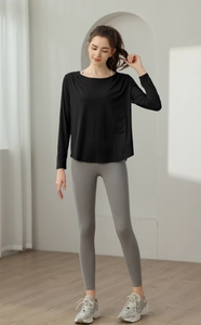 Detail von lockerem schwarzem Langarm-Yoga-Oberteil und grauen Kompressions-Leggings