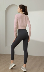 Rear view of a woman wearing a pink jacquard long sleeve yoga top and grey leggings