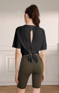 Detail of black breathable yoga top with cross tie back design and split hem detail