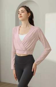 Detail of pink long-sleeve cross-front yoga top with white sports bra and grey leggings