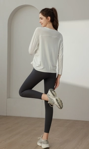 Lockeres weißes Langarm-Sportoberteil kombiniert mit grauen Yoga-Leggings mit hoher Taille
