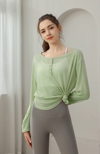 Détail du haut de yoga en maille vert clair avec col boutonné et ourlet noué à la taille