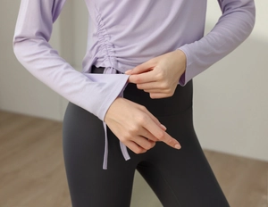 Detail of adjustable side drawstrings on lavender long sleeve yoga top for women