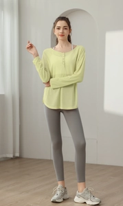 Détail du haut de yoga en maille vert clair avec col boutonné et leggings de sport gris