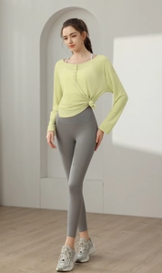 Détail du haut de yoga noué vert clair et du legging gris à taille haute