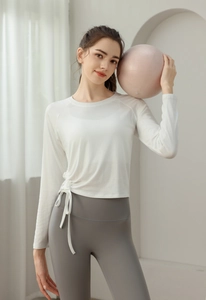 Detail of white long sleeve yoga top featuring adjustable side drawstring and ruching