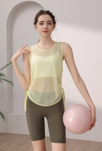 Detail of light yellow mesh yoga tank top with side drawstring hem and green cycling shorts