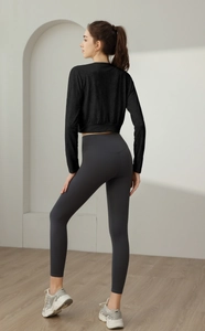 Side view of woman in black long sleeve crop top and grey high waist fitness leggings