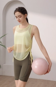 Detail of breathable yellow mesh yoga vest with side drawstring and green shorts