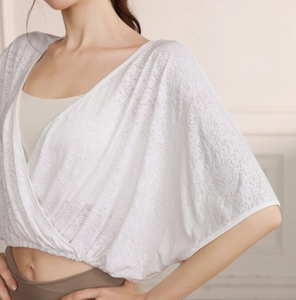 Close-up of white jacquard lace yoga top featuring batwing sleeves and wrap design