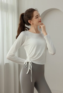 Detail of adjustable side drawstring on white long sleeve slim fit yoga top for women