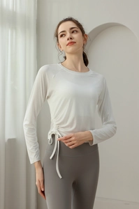 Detail of adjustable drawstring cinch on side of white long sleeve slim yoga shirt