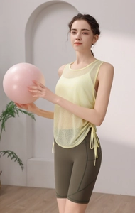 Detail of light yellow mesh yoga tank top with side drawstring and green high waist shorts