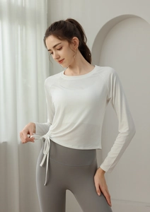 Detail of white long sleeve yoga top with side drawstring ties and ruched slim fit texture