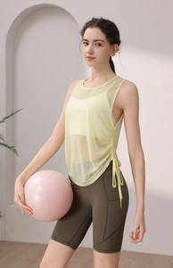 Detail of light yellow breathable mesh yoga top with side drawstring design and green shorts